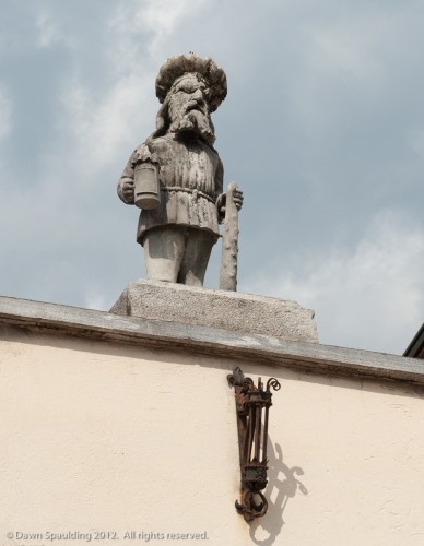 Figurine keeping watch atop an arcaded building